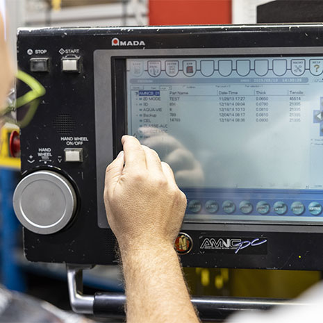 Une main entrain de vérifier quelque chose sur un écran tactile d'une machine.