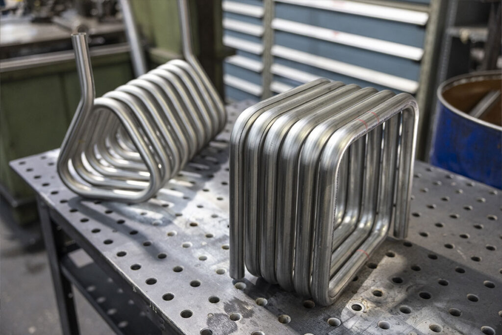 Pièces métalliques cintrées alignées sur une table de travail dans un atelier de fabrication industrielle.